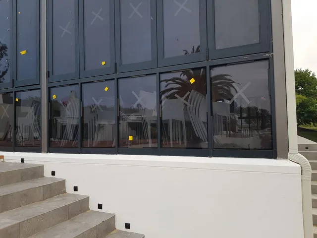 Dark aluminium glazed facade beside exterior steps