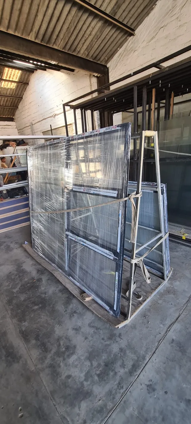 White aluminium frame sections stacked in the workshop