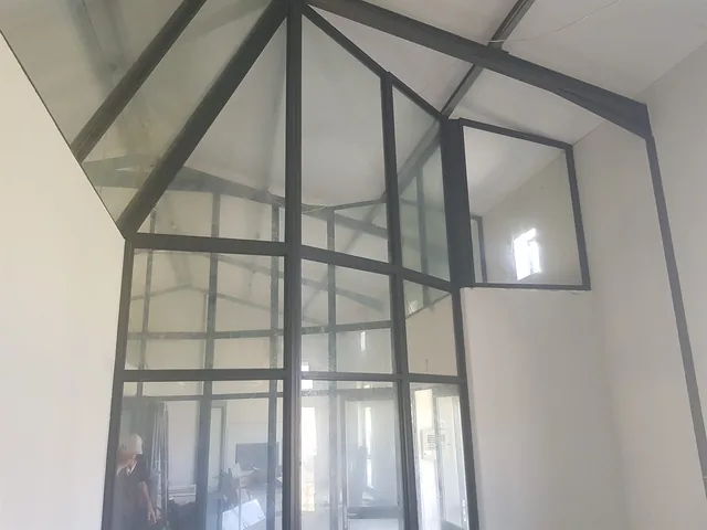Black-framed interior glazed partition under a pitched ceiling