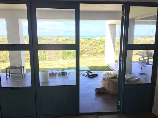 Dark aluminium doors framing a coastal view